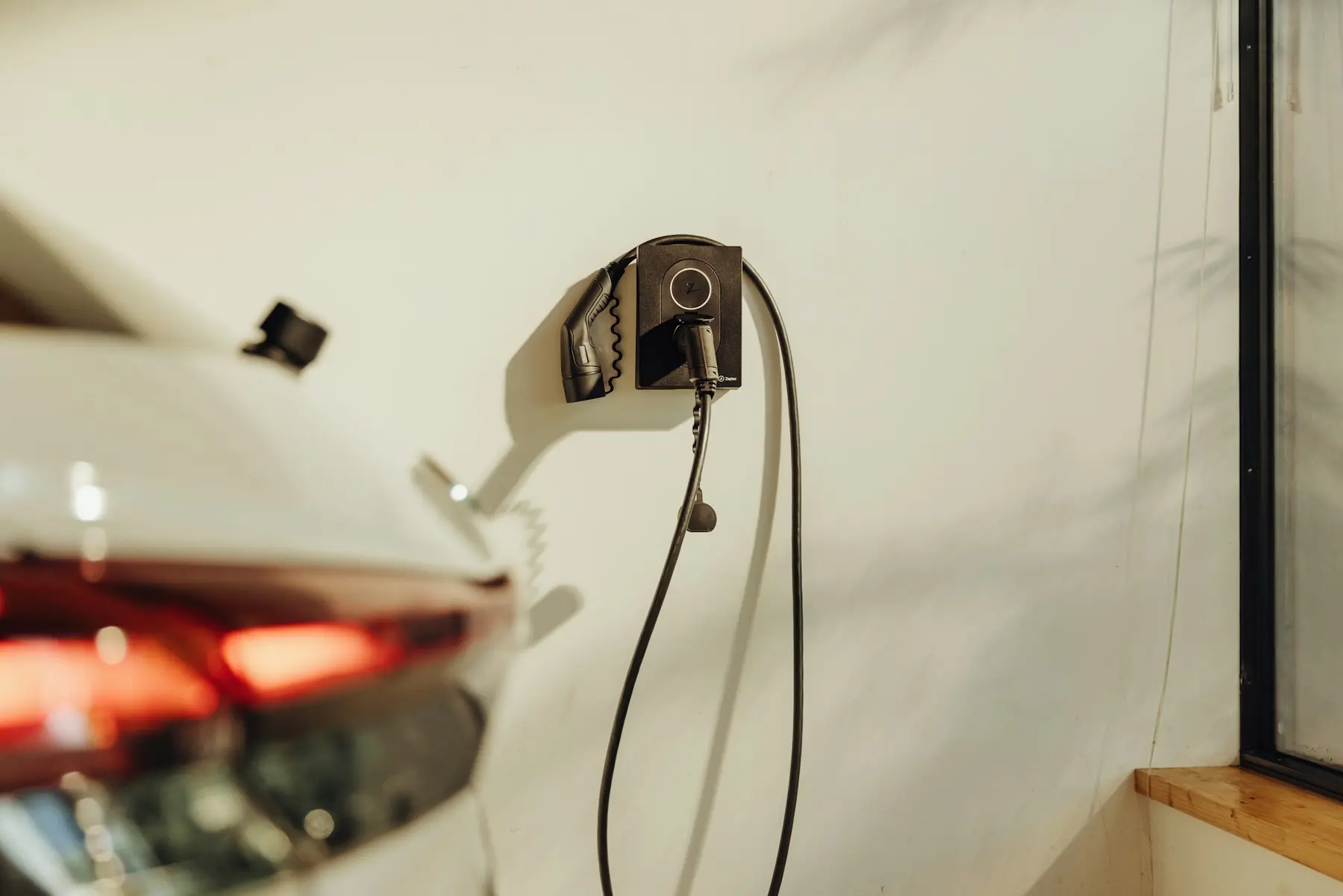 A wall-mounted EV charger on a timber fence