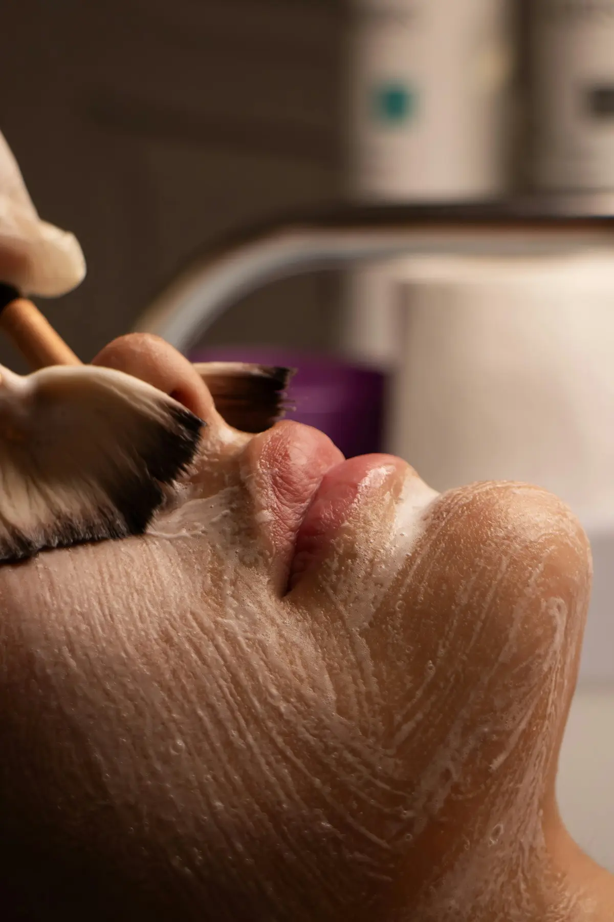 A brush applying a skin peel along a client's jaw