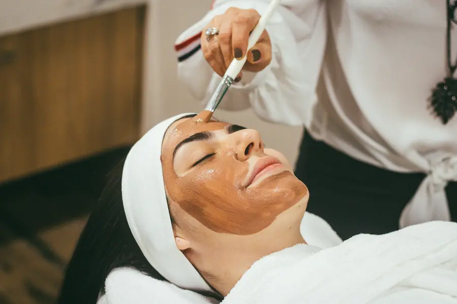 A practitioner brushing a clay mask onto a client's face