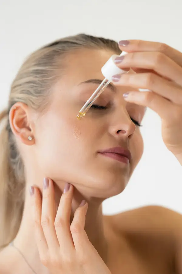 A woman applying a drop of serum to her forehead
